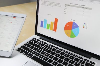 Laptop displaying charts and graphs with tablet calendar for data analysis and planning.