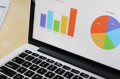 Laptop displaying charts and graphs with tablet calendar for data analysis and planning.